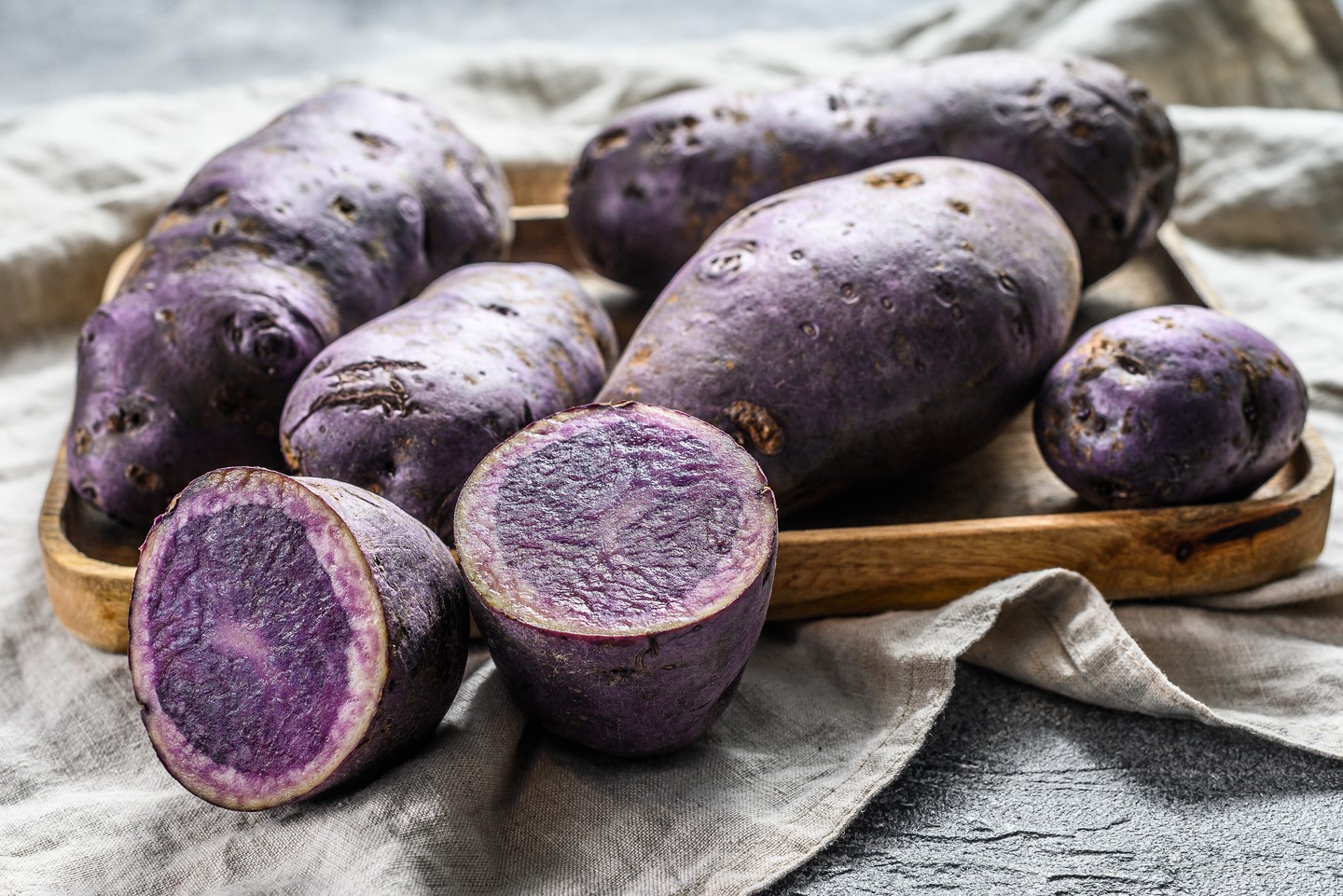 Raw purple potatoes on a chopping Board. Gray background. Top view