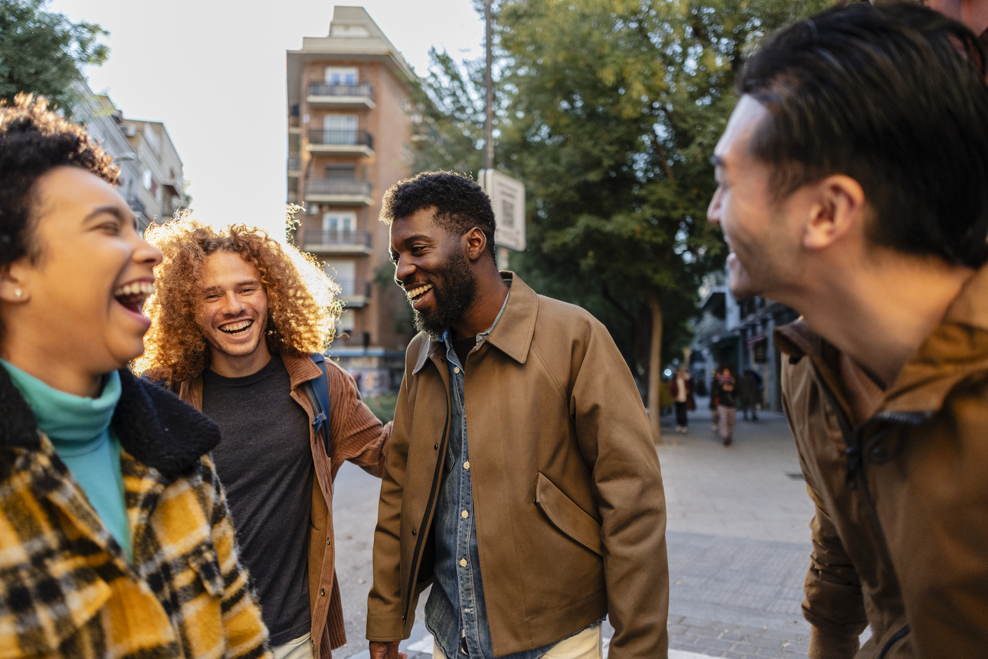 Happy multi ethnic friends laughing and walking together in a city street